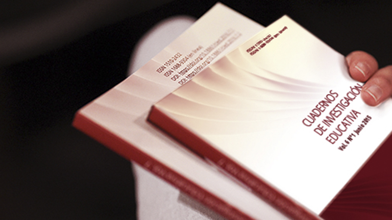 A hand holding a copy of the journal *Cuadernos de Investigación Educativa*