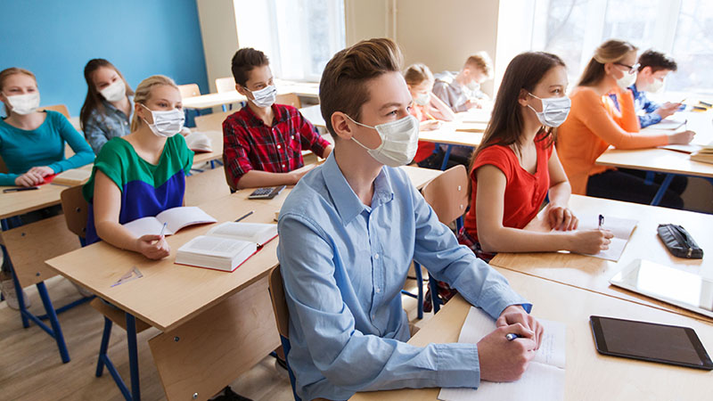 A group of students in a classroom, wearing face masks