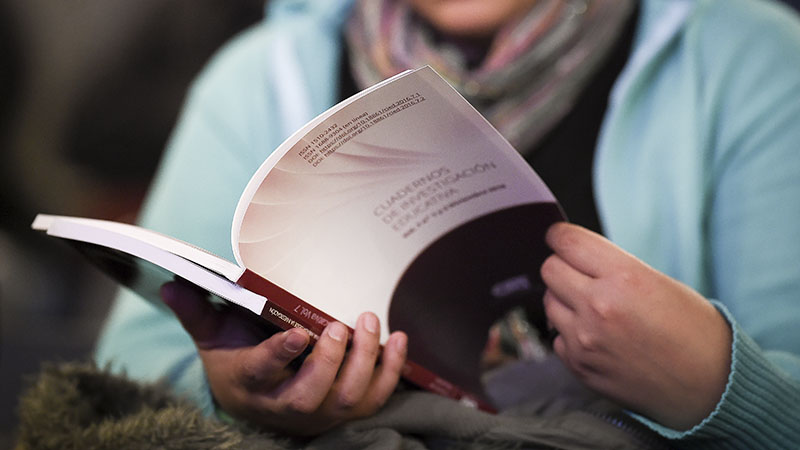 Hand holding a copy of *Cuadernos de Investigación Educativa*