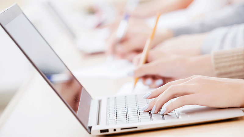 A hand working on a laptop