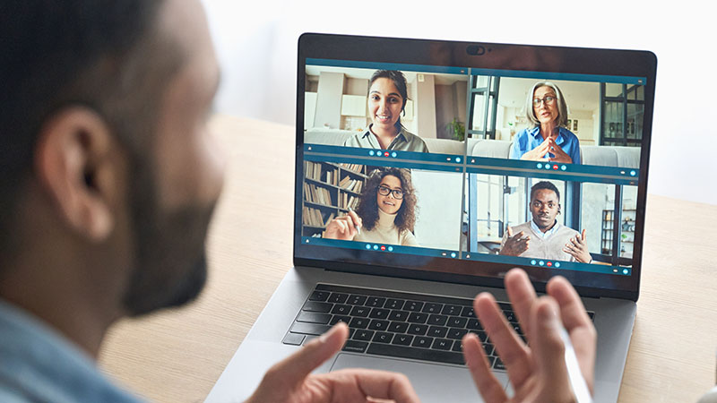 A young person looking at a computer screen showing a video conference
