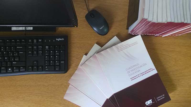A desk with a computer, a mouse, and an issue of *Cuadernos de Investigación Educativa*