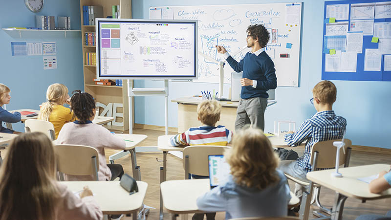 An English teacher working in a classroom with his students