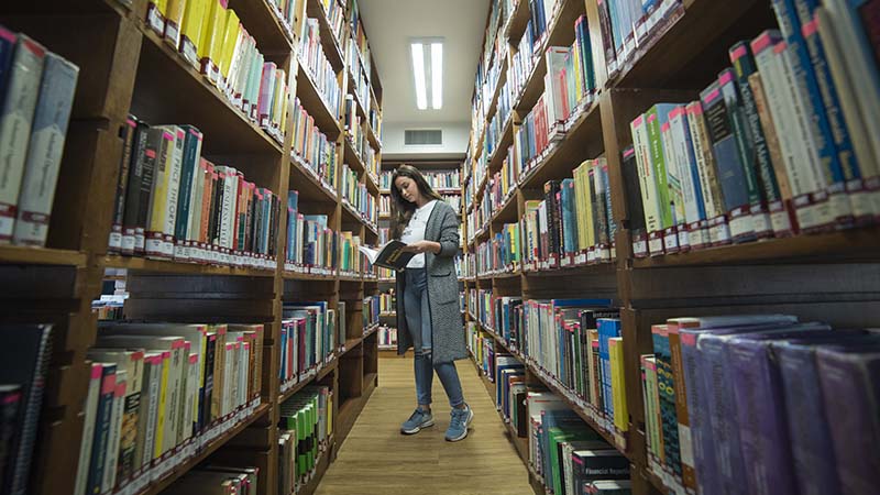 A woman in a library, reading a book