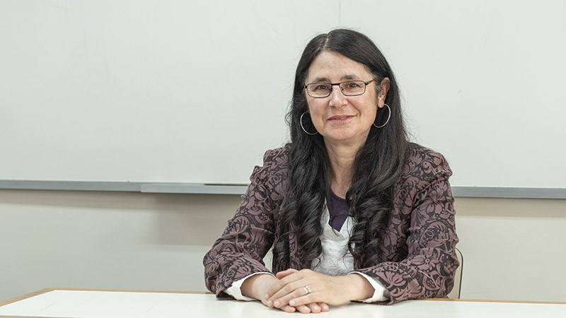 Claudia Cabrera Borges at a desk, with a whiteboard behind her