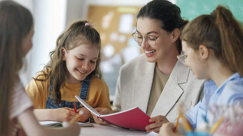 A teacher working with a group of children at a table
