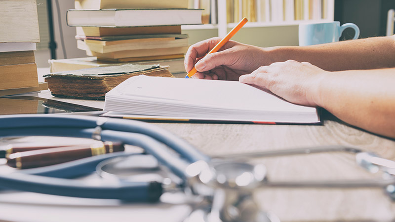 Hands working at a desk, with a stethoscope visible