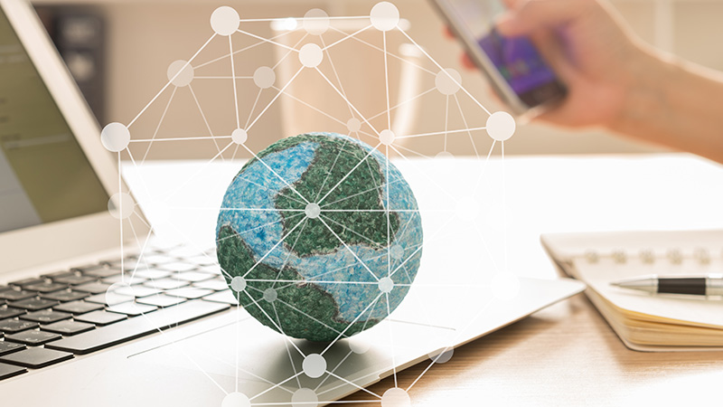 A globe on a desk, with a computer and papers behind it