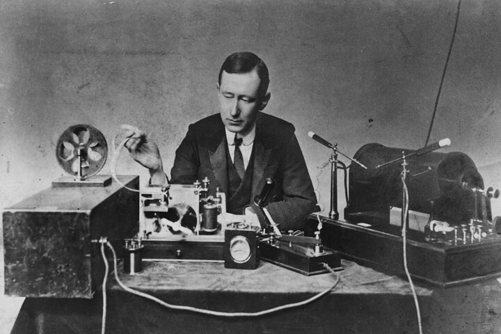 *Ingeniero eléctrico Guglielmo Marconi con transmisor de chispa (derecha) y receptor de cohesión (izquierda), utilizados en algunas de sus primeras transmisiones radiotelegráficas de larga distancia durante la década de 1890.*